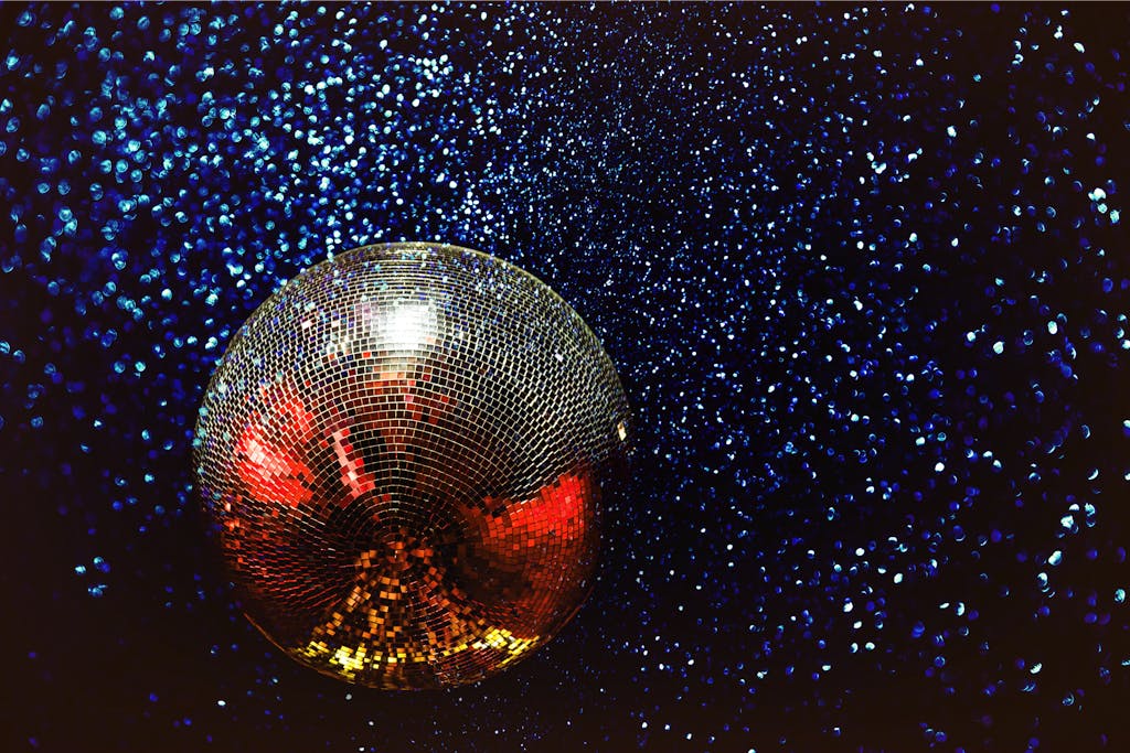 Shining disco ball with colorful reflections in a dark, starry background.